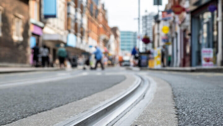 British high street shops close focused in tram tracks on the road- Croydon, South London